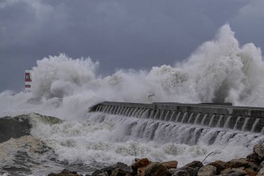 Fırtınalı dalga sıçraması. Douro nehri ağzı kuzey rıhtımı ve işaret fişeği.