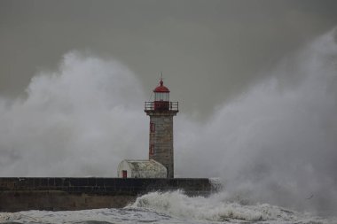 Büyük dalga sıçraması. Douro nehri ağzı eski iskele ve deniz feneri. İlginç bir ışık..