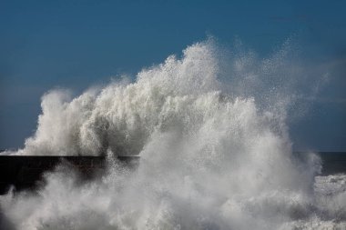Fırtınalı beyaz dalga mavi gökyüzüne vuruyor