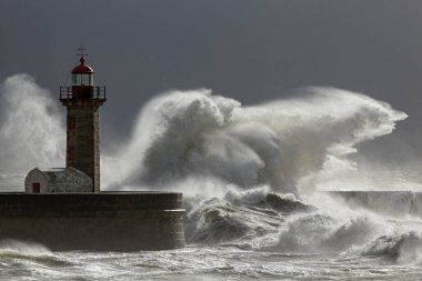 Huge stormy wave splash. Douro river mouth old lighthouse and granite pier, Porto, Portugal.