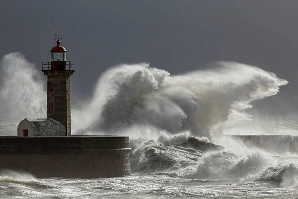 Huge stormy wave splash. Douro river mouth old lighthouse and granite pier, Porto, Portugal.