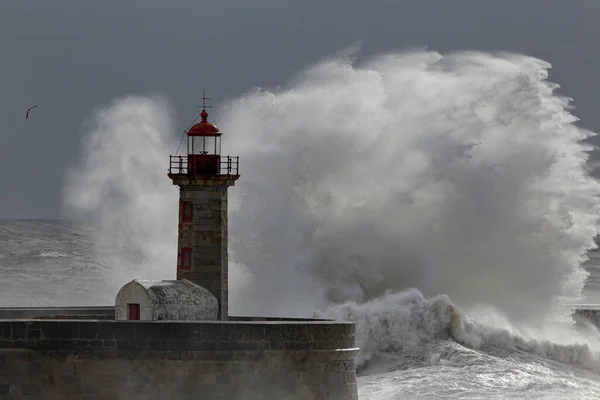 Dramatic seascape with big stormy waves splash over old lighthouse