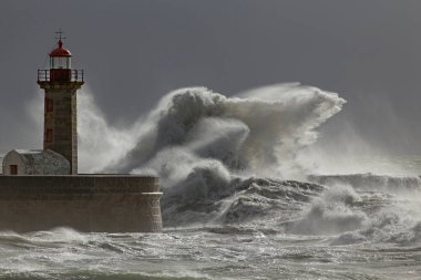 Dramatic seascape with big stormy waves splash over old lighthouse