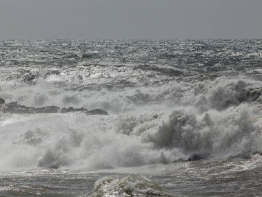Stormy seascape with breaking waves against rocks in the foreground