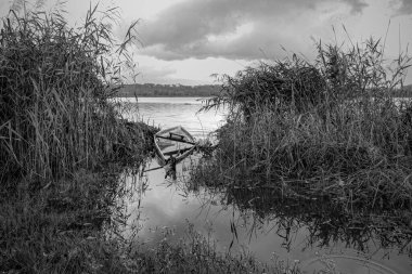 Dramatic view of Pateira de Fermentelos lagoon seeing a sunken traditional wooden fishing boat. Converted black and white.
