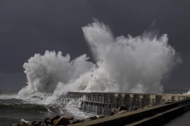 Fırtınalı dalga sıçraması. Douro nehri ağzı kuzey rıhtımı ve deniz feneri. Kasırga sırasında