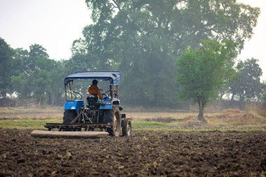 TIKAMGARH, MADHYA PRADESH, Hindistan - Mayıs 02, 2022: Tarım alanında traktörle çalışan Hintli çiftçi.