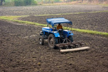 TIKAMGARH, MADHYA PRADESH, Hindistan - Mayıs 02, 2022: Tarım alanında traktörle çalışan Hintli çiftçi.