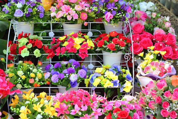 Hermosa de flores artificiales en los estantes . — Foto de Stock