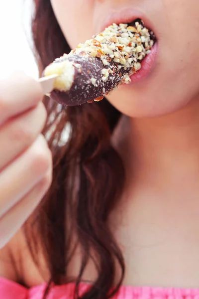 Jovencita comiendo plátanos recubiertos de chocolate decorados con crujiente — Foto de Stock