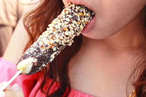 Jovencita comiendo plátanos recubiertos de chocolate decorados con crujiente — Foto de Stock