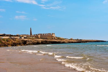 Arka plandaki sampieri plajı Ragusa Sicilya 'daki eski bir tuğla fabrikasının kalıntıları.