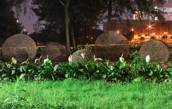 Cama de flores com bolas torcidas com uma luz noturna. Macau — Fotografia de Stock