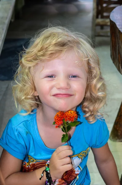Blond child and an orange flower — Stock Photo, Image