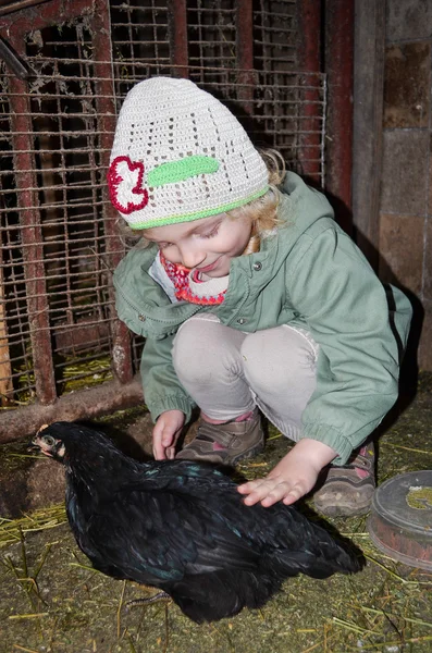 Chica acariciando una gallina negra — Foto de Stock