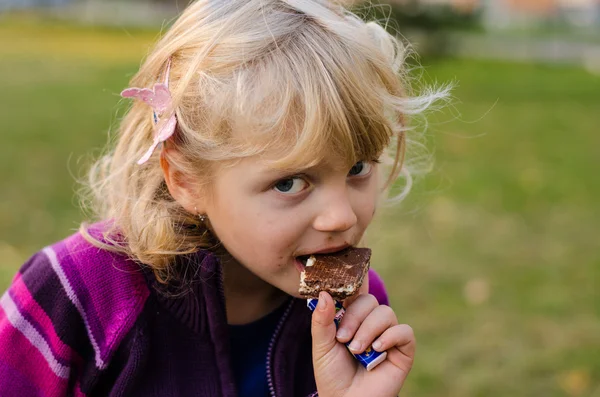 Chica rubia comiendo una galleta de chocolate — Foto de Stock