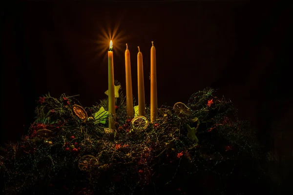 Одна Сияющая Свеча Красочном Украшенном Венке Четырьмя Свечами Черном Фоне — стоковое фото