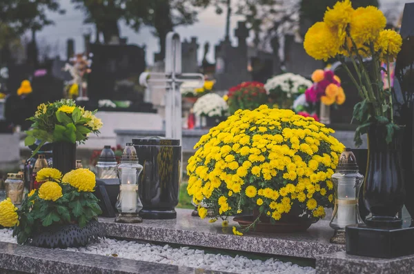 graves, yellow chrysanthemum flowers, decoration and candles during all saints day on cemetery, funeral concept