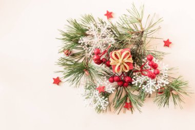 Kırmızı Noel hediye kutusu, kırmızı çoban püskülü, yıldızlar ve beyaz arka planda yeşil çam ağacı süslemesi.