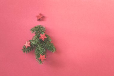 Çam dalı ve kırmızı arka planda kırmızı süslemeleri olan basit bir Noel ağacı.