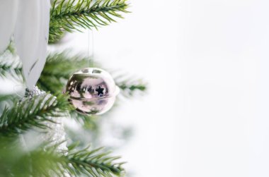 Beyaz arka planlara karşı ağaçta gümüş Noel çanı süslemesi