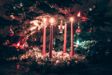 Arka planda aydınlatılmış noel ağacıyla gelen 3. mumu yakmak