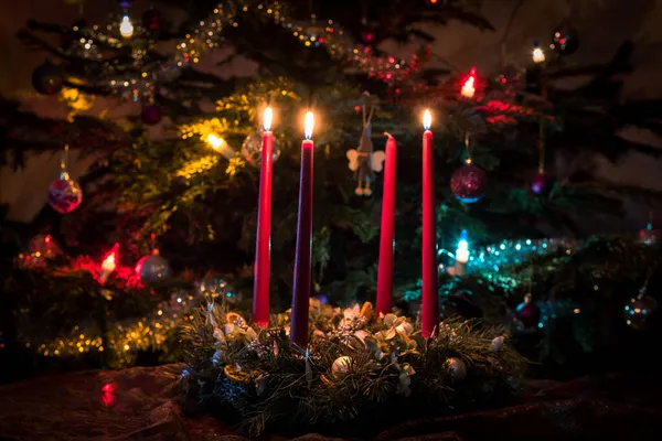 Hořící Adventní Svíčka Osvětleným Vánoční Strom Pozadí — Stock fotografie