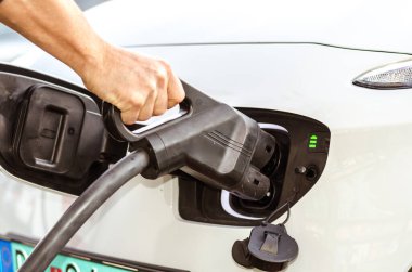 EV şarj istasyonunda şarj eden eko yeşil alternatif elektrikli araçla insan eli