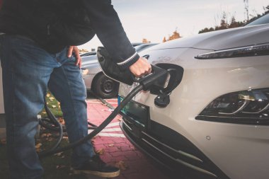 EV şarj istasyonunda şarj eden eko yeşil alternatif elektrikli araçla insan eli