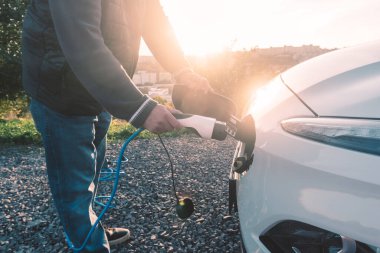 EV şarj istasyonunda şarj eden eko yeşil alternatif elektrikli araçla insan eli