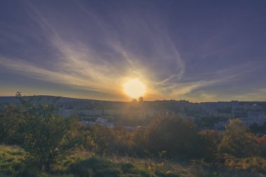 Etrafı çalılarla ve ağaçlarla çevrili düzlüklerin üzerinde sonbahar günbatımının güzel renkleri