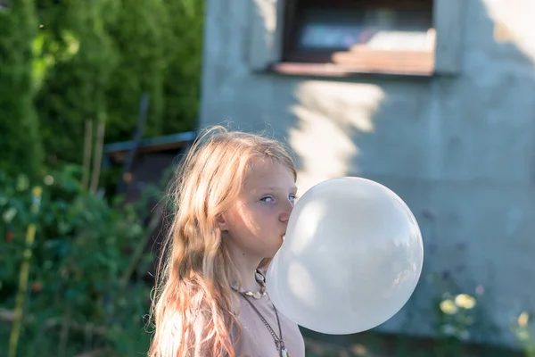 cute girl with huge chewing gum bubble in the green garden