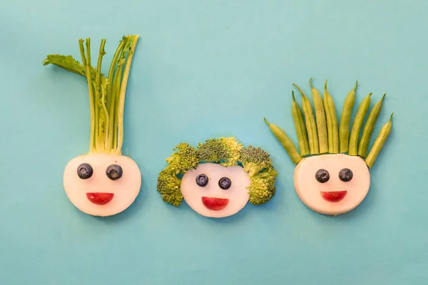 funny faces from blackberry, beans, broccoli and white raddish, creative way on the plate isolated