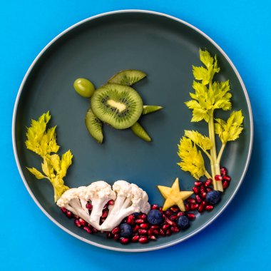 Deniz dünyasındaki kaplumbağa, mercan ve bitkiler böğürtlenler, kivi, salata ve karnabahar tabaktaki izole renkli gıda fikirleri, kopyalama alanı