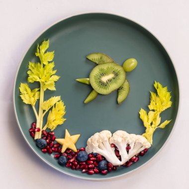 Deniz dünyasındaki kaplumbağa, mercan ve bitkiler böğürtlenler, kivi, salata ve karnabahar tabaktaki izole renkli gıda fikirleri.