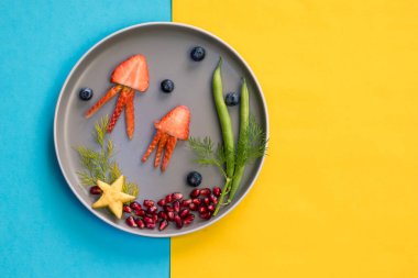 Çilek, böğürtlen, fasulye ve nar gibi sarı arkaplanlı tenha yemek fikirlerinden denizanası, yeşil bitkiler ve deniz yıldızı.