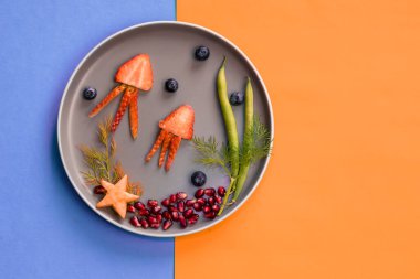 Çilek, böğürtlen, fasulye ve nar denizanası denizyıldızı tabağında mavi turuncu arka plan ile izole edilmiş renkli gıda fikirleri