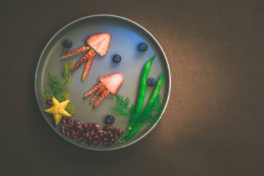 Çilek, böğürtlen, fasulye ve nar gibi kahverengi arkaplanlı tenha yemek fikirlerinden denizanası, yeşil bitkiler ve deniz yıldızı.