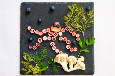 ahtapot deniz dünyası ile kırmızı meyvelerden yapılır karnabahar ve siyah arka planda yeşil otlar