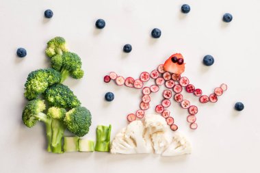 ahtapot kırmızı meyvelerden yapılmış deniz dünyası karnabahar, brokoli ve yeşil otlar beyaz arka planda izole edilmiş.