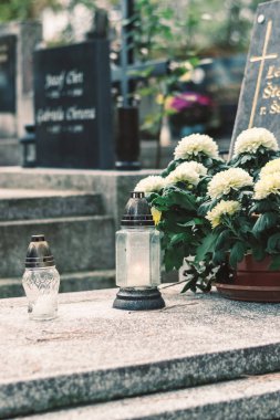 Mezarda yanan mum ve kasımpatı çiçeği dekoru.