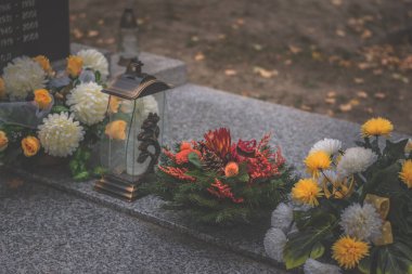 Mezarda yanan mum ve kasımpatı çiçeği dekoru.