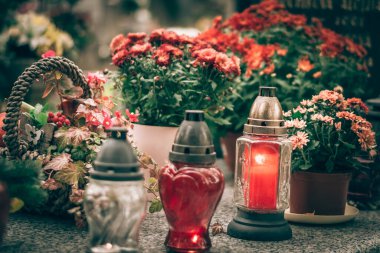 Mezarda yanan mum ve kasımpatı çiçeği dekoru.