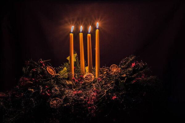 4 burning advent candles on black background