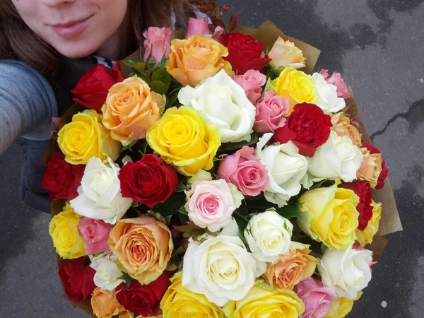 Entrega de colorido ramo de rosas por sonriente joven —  Fotos de Stock