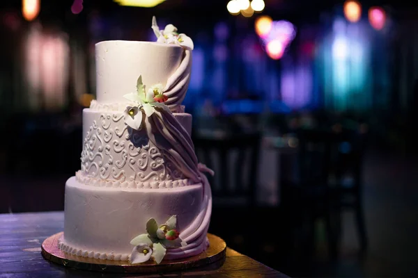 Wedding venue - green and purple restaurant hall, with neon lighting, white three tiered cake.