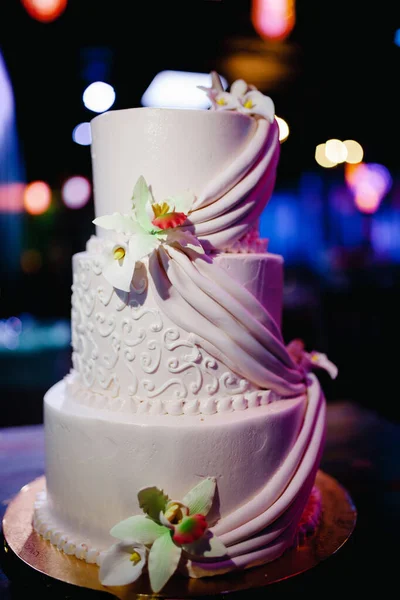 Wedding venue - green and purple restaurant hall, with neon lighting, white three tiered cake.