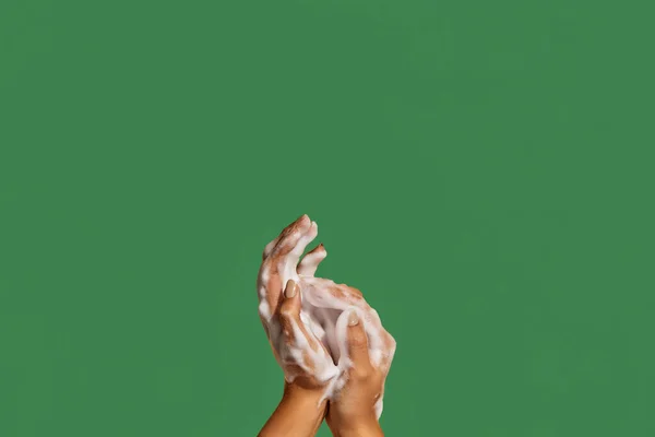 Two hands with hand soap foam on colorful background with copy space.