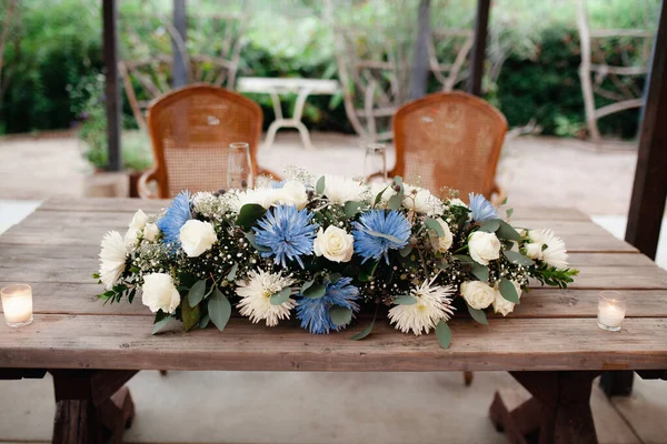 Sweethearts table - wooden rustic table with beautiful florals.  White roses, blue and purple chrysanthemum, eucalyptus leaves, baby breaths floral arrangement