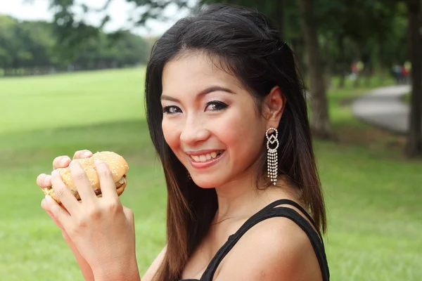 Mujer joven disfrutando de una hamburguesa de pollo — Foto de Stock